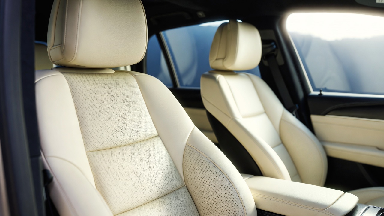 Close-up precision cleaning of air vents and leather stitching during interior detail